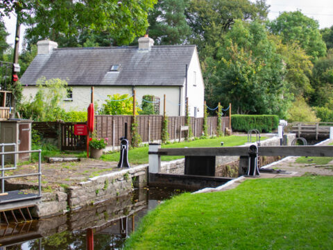 A view of the lock and lock cottage at Brynich south of Brecon. The lock is empty and the grass and trees are vibrant and green.
